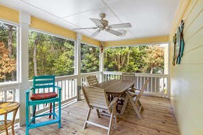 Enjoy outdoor dining or relaxation on this covered porch with a table and chairs, surrounded by a white railing and ceiling fan.