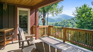 A wooden deck with outdoor furniture, a view of mountains, and a door leading to the interior. - Grand Oaks B6- Mountain Condo, Gated Resort, Indoor/Outdoor Pools & Hot Tub (Boone)