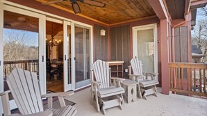 A covered porch with Adirondack chairs, a table, and a ceiling fan. - Grand Oaks B6- Mountain Condo, Gated Resort, Indoor/Outdoor Pools & Hot Tub (Boone)