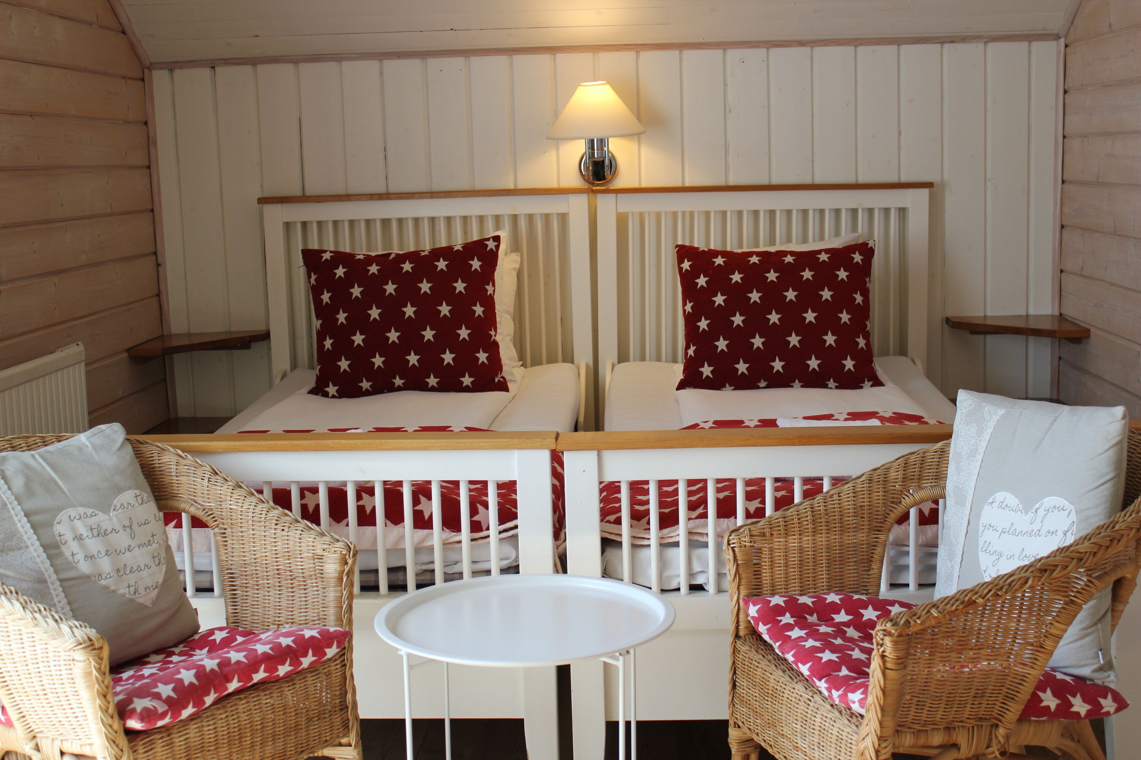 A cozy room with two beds, a small table, and wicker chairs.