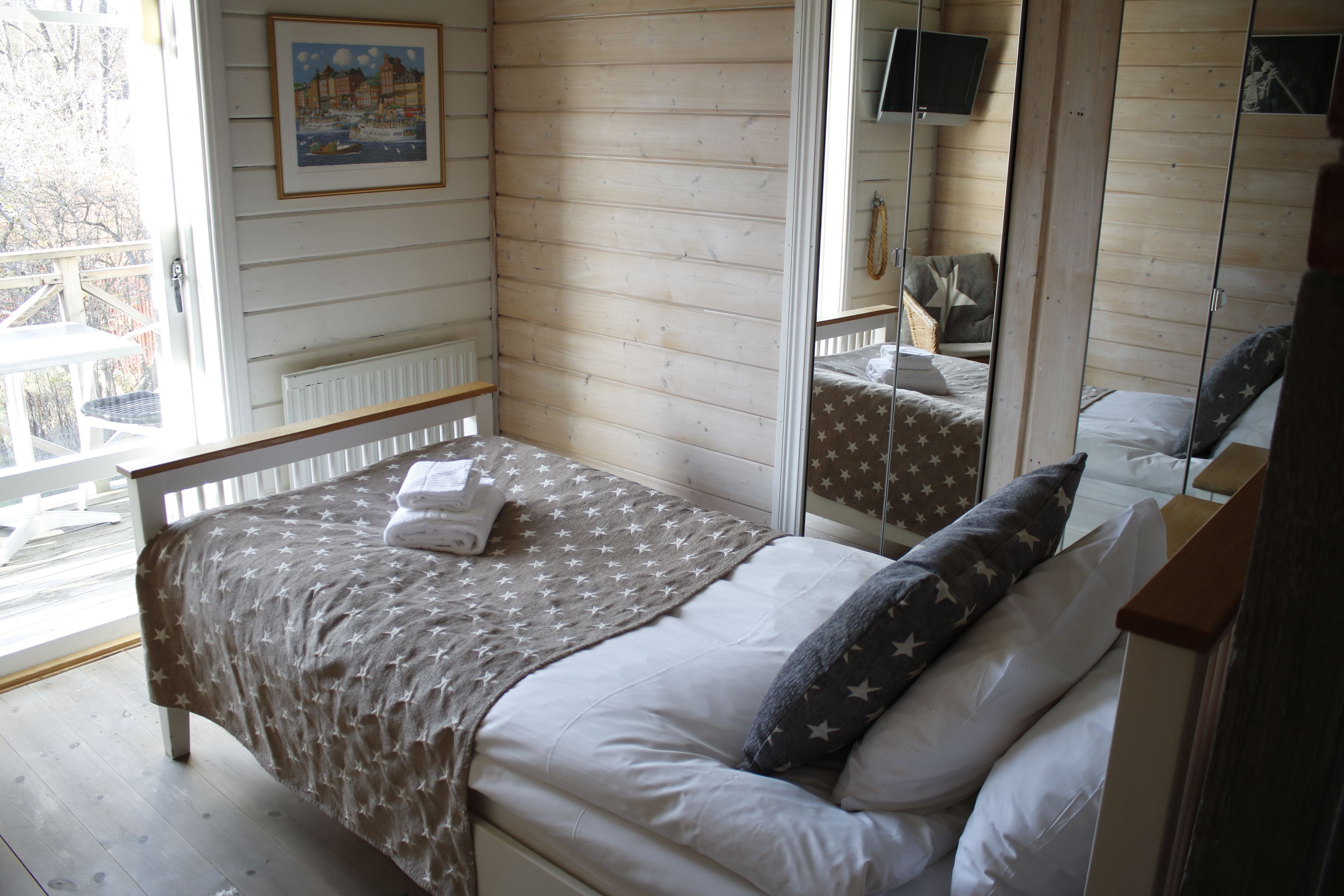 Een slaapkamer met een bed, een raam, een spiegel en een deur.