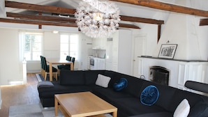 Een moderne woonkamer met een hoekbank, een houten salontafel en een kroonluchter.