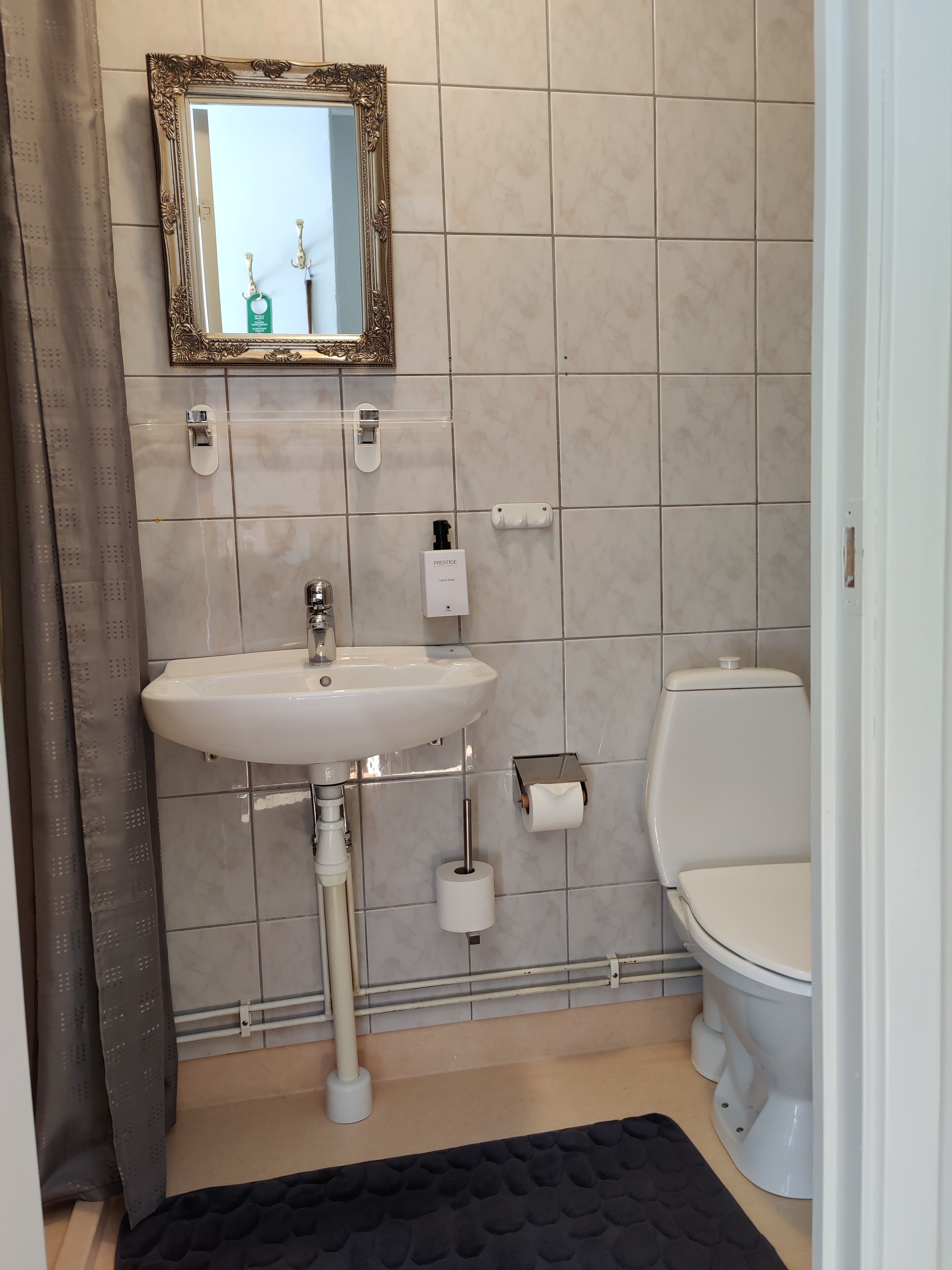 A bathroom with a white sink, toilet, and a mirror with an ornate frame.