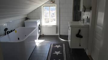 Ett badrum med badkar, dusch, handfat och ett fönster.