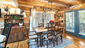 A rustic wooden interior with a dining table set for six, surrounded by wooden chairs. - A Portofino Cabin: Mountain Log Cabin, Hot Tub, Pet Friendly, Wood Fireplace (Seven Devils)