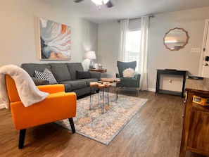 Una sala de estar con sofá, sillón, mesa de centro y alfombra.