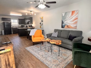 Una sala de estar moderna con un sofá gris, un sillón naranja y una mesa de centro con un alfombra.