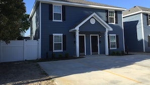 A two-story residential building with a dark blue exterior, white trim, and a central entrance with a small porch. - Awesome Location 2 Bedroom 2.5 Bath / 511B (Lake Charles)