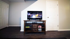 A TV on a wooden entertainment center in a room with dark flooring and white walls. - Awesome Location 2 Bedroom 2.5 Bath / 511B (Lake Charles)