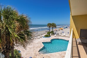 A pool area with a view of the beach, a palm tree, and a chair. - Stay @ Peaches & Cream on Folly Beach (Folly Beach)