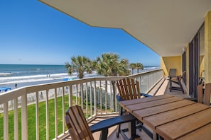 A balcony with a view of the beach, wooden chairs, and a table. - Stay @ Peaches & Cream on Folly Beach (Folly Beach)