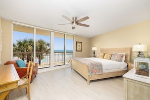 A bedroom with a bed, a desk, a chair, a ceiling fan, and a view of the beach. - Stay @ Peaches & Cream on Folly Beach (Folly Beach)