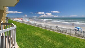 Un balcon avec vue sur une plage, une jetée et l’océan.