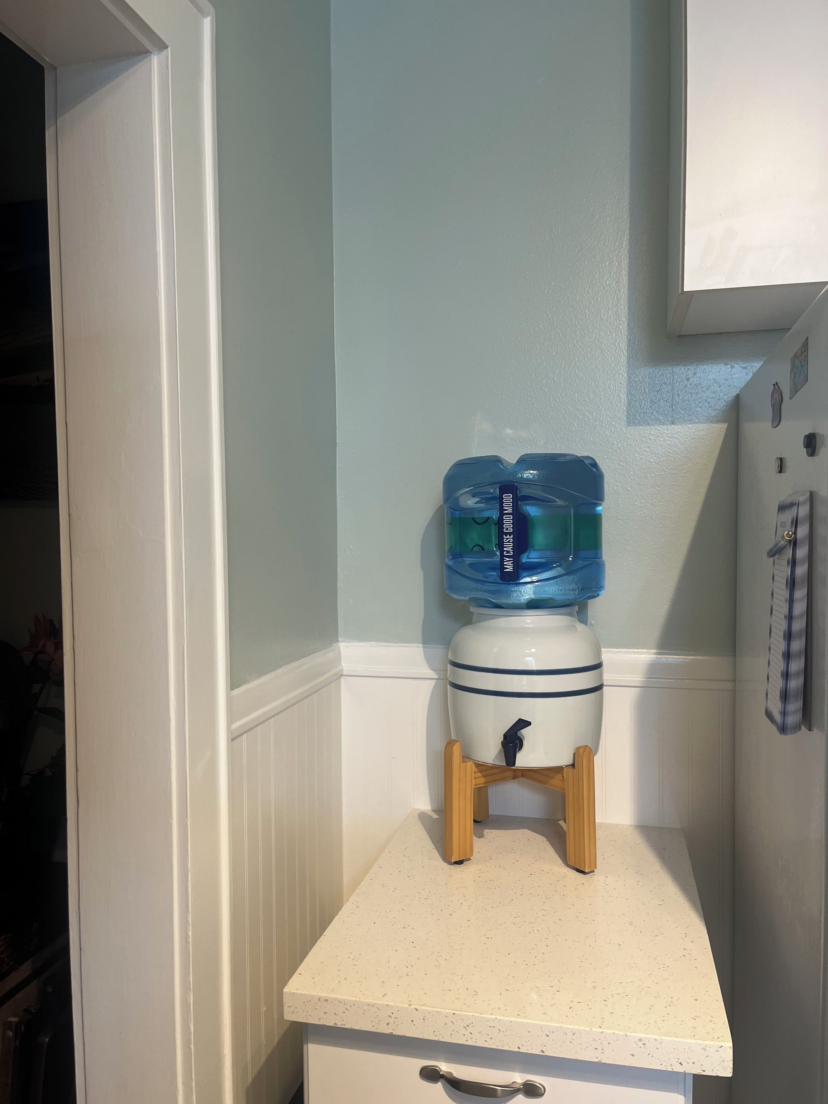 Una cocina con mostrador, dispensador de agua y refrigerador.