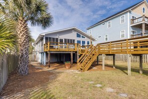 A two-story house with a wooden deck and a staircase leading to a covered area.