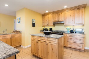 A kitchen with wooden cabinets, granite countertops, a stove, and a microwave. - Stay @ Fun in the Sun! (Folly Beach)
