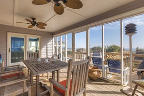 A sunlit room with a large window, a wooden table, and a ceiling fan.