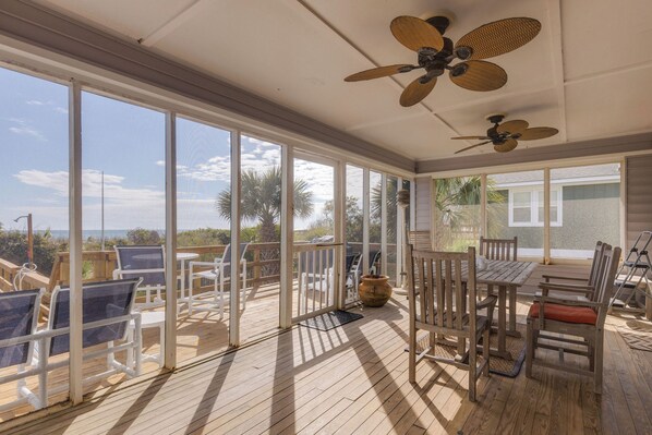 A covered outdoor area with a table and chairs, a ceiling fan, and a view of the outdoors. - Stay @ Fun in the Sun! (Folly Beach)