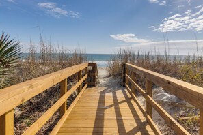 A wooden boardwalk leading to a beach with sand and seaweed on either side. - Stay @ Fun in the Sun! (Folly Beach)