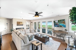 A spacious living room with a large sofa, a coffee table, and a ceiling fan. - Grand Oaks RR4- Mountain Condo, Gated Resort, Indoor/Outdoor Pools & Hot Tub (Banner Elk)