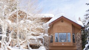 A wooden cabin with a stone foundation, a garage, and a snow-covered landscape. - Luxury home less than a mile from Deer Valley with free shuttle to and from DV (Park City)