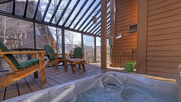 A hot tub area with wooden deck chairs and a wooden table, surrounded by glass walls. - Luxury home less than a mile from Deer Valley with free shuttle to and from DV (Park City)