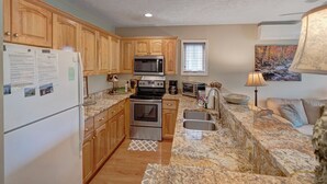 A compact kitchen with wooden cabinets, a refrigerator, a microwave, an oven, and a sink. - Hawks Peak South 221-Mtn Condo, Near High Country Attractions, ZipLining, Hiking (Seven Devils)