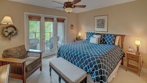 A bedroom with a bed, a bench, a chair, a ceiling fan, and a door leading to an outdoor area. - Hawks Peak South 221-Mtn Condo, Near High Country Attractions, ZipLining, Hiking (Seven Devils)