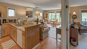 A spacious kitchen with wooden cabinets, a central island, and a dining area with a table and chairs. - Hawks Peak South 221-Mtn Condo, Near High Country Attractions, ZipLining, Hiking (Seven Devils)