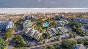 Un hotel en la costa con varias edificaciones, una piscina central y vista al mar.