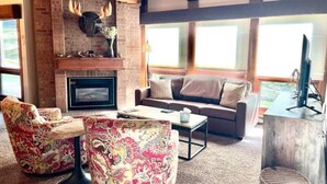 Una sala de estar acogedora con chimenea, muebles con diseños y un ventanal grande.