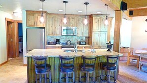 Una cocina con armarios de madera, una isla grande con taburetes de bar, un microondas y un fregadero.