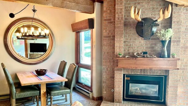 Una sala de estar acogedora con chimenea, un espejo redondo y un comedor con mesa y sillas.