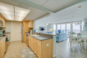 Une cuisine spacieuse avec des meubles en bois, un grand îlot central et une vue sur un balcon.