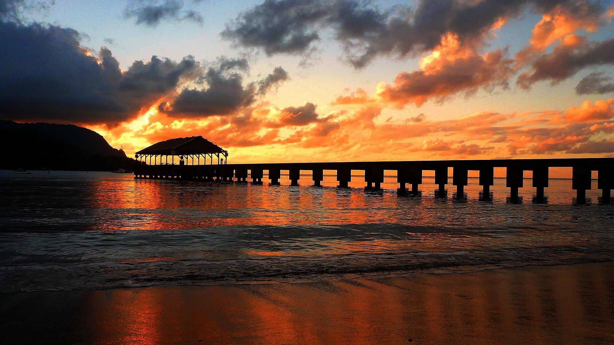A pier extending into calm waters with a structure at the end.