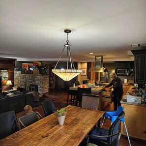 A spacious living room with a wooden dining table, a fireplace, and a kitchen area with modern appliances. - Private Ranch House Resort (Templeton)