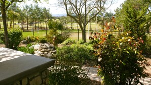 A landscaped garden with a stone bench, a variety of shrubs, and a metal fence. - Private Ranch House Resort (Templeton)