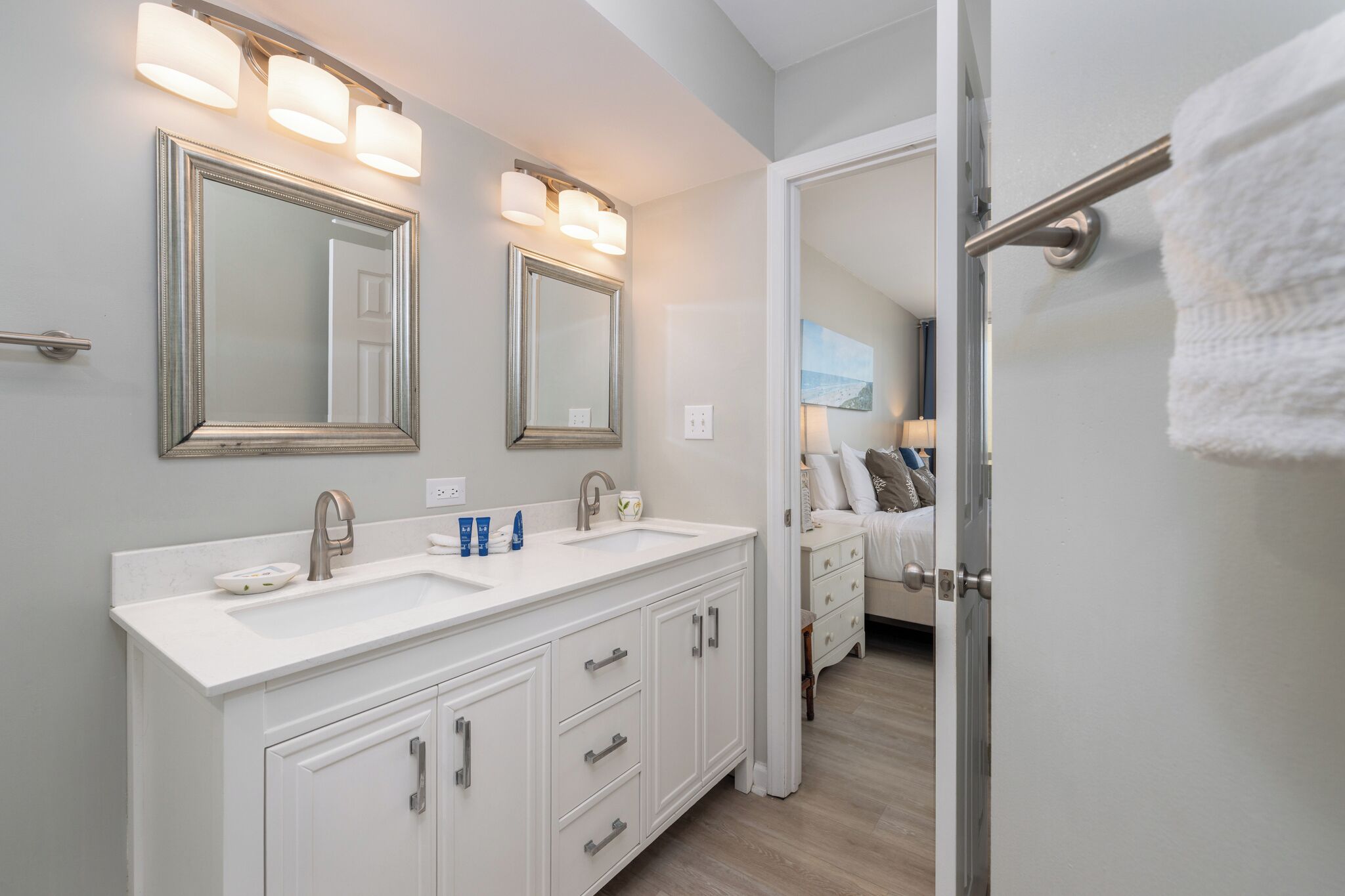 A bathroom with a double sink, two mirrors, and a towel rack.