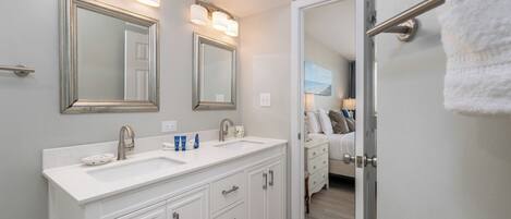 A bathroom with a double sink, two mirrors, and a towel rack.
