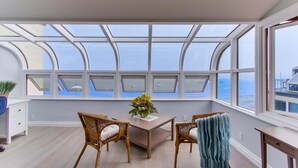 A room with a large skylight, a wooden table with chairs, and a view of the sea. - Right On The Beach! Exquisitely Remodeled 3BR/3BA . Perfect For Families. (San Diego)