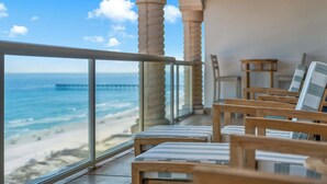A balcony with wooden chairs and a view of the ocean and pier. - Beach Club 1005 - 𝑨𝒒𝒖𝒂 𝑶𝒂𝒔𝒊𝒔 (Pensacola Beach)