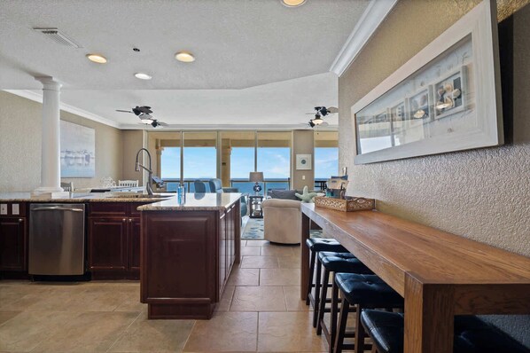 A spacious kitchen with a large island, bar seating, and a view of the ocean.