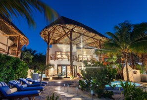 A resort with a pool, lounge chairs, and a thatched-roof structure.