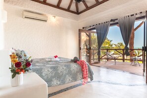 A bedroom with a bed, a vase of flowers, and a view of the outdoors.