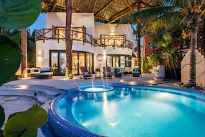 A pool area with a hot tub, lounge chairs, and a covered seating area.