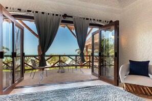 A room with a view of the beach, a hammock, a chair, and a sofa.