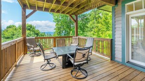A covered outdoor deck with a table and chairs, overlooking a forested area. - Townhome R5B- Mtn Home/View, Foosball, Indoor/Outdoor Pools & Hot Tub, Fireplace (Banner Elk)
