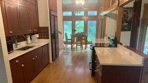 Une cuisine moderne avec des meubles en bois, un grand îlot central et un coin repas comprenant une table et des chaises.