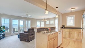 A spacious living area with a sofa, a kitchen island with a sink, and a balcony with a view. - Wintergreens R1012- Mtn Condo/View, Gated Resort, Indoor/Outdoor Pools & Hot Tub (Boone)