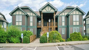 A multi-story building with a central entrance, wooden railings, and a wheelchair-accessible ramp. - Wintergreens R1012- Mtn Condo/View, Gated Resort, Indoor/Outdoor Pools & Hot Tub (Boone)